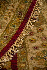 Detalle de alfombra redonda doblada con flecos artesanales y guarda decorativa de inspiración oriental.