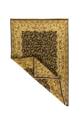 Alfombra rectangular de estilo clásico con esquina doblada que muestra el reverso del tejido y el detalle del borde floral