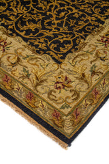 Primer plano lateral de alfombra tradicional con patrón vegetal dorado sobre fondo oscuro y borde ornamental claro