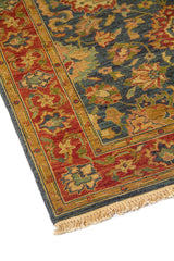 Primer plano lateral de alfombra tradicional con patrón floral simétrico y borde decorativo en rojo, dorado y azul