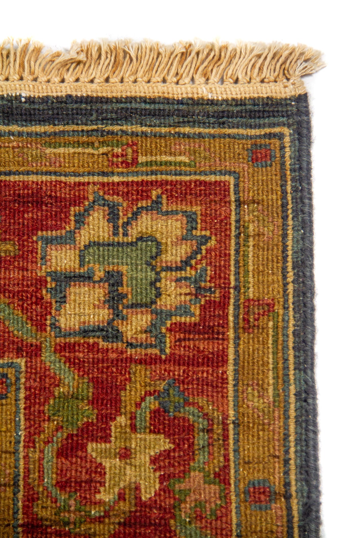 Detalle de flecos y esquina de alfombra oriental con marco geométrico sutil y diseño floral en tonos cálidos y azulados