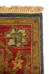 Detalle de flecos y esquina de alfombra oriental con marco geométrico sutil y diseño floral en tonos cálidos y azulados