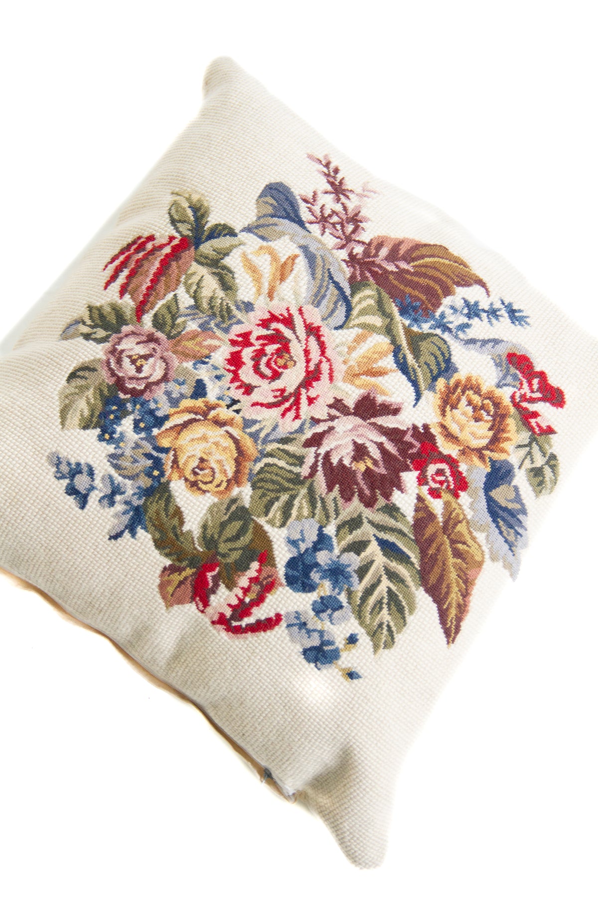 Detalle de textura de almohadón gobelino con flores y hojas en tonos rojos, azules, verdes y amarillos