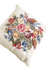 Detalle de textura de almohadón gobelino con flores y hojas en tonos rojos, azules, verdes y amarillos