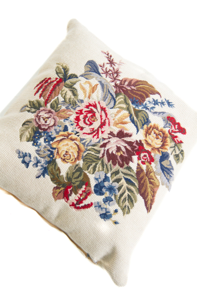 Detalle de textura de almohadón gobelino con flores y hojas en tonos rojos, azules, verdes y amarillos