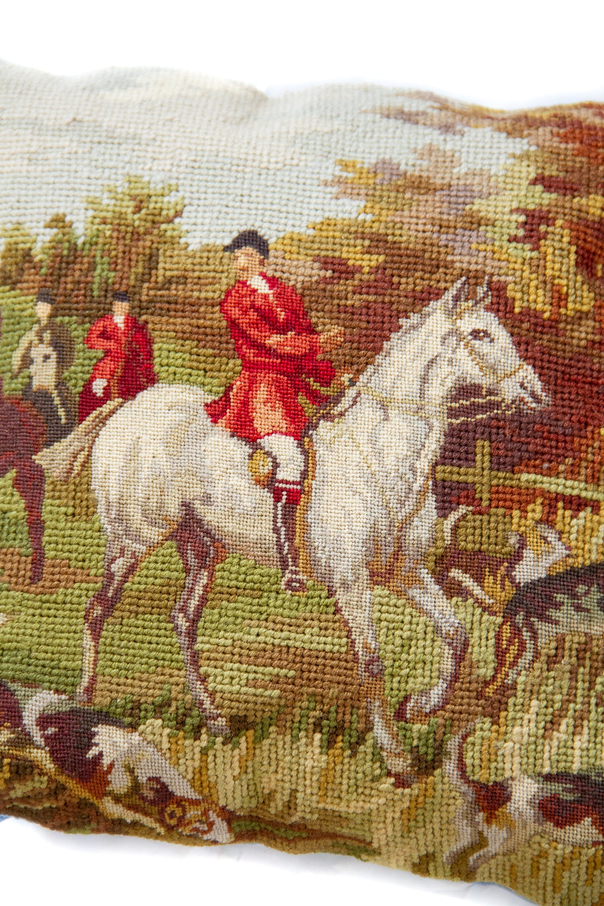 Detalle de textura de almohadón gobelino con diseño de caballo, jinetes y paisaje en tonos verdes y marrones