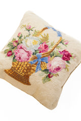 Detalle de textura de almohadón beige con flores, hojas y canasto en tonos rosas y azules