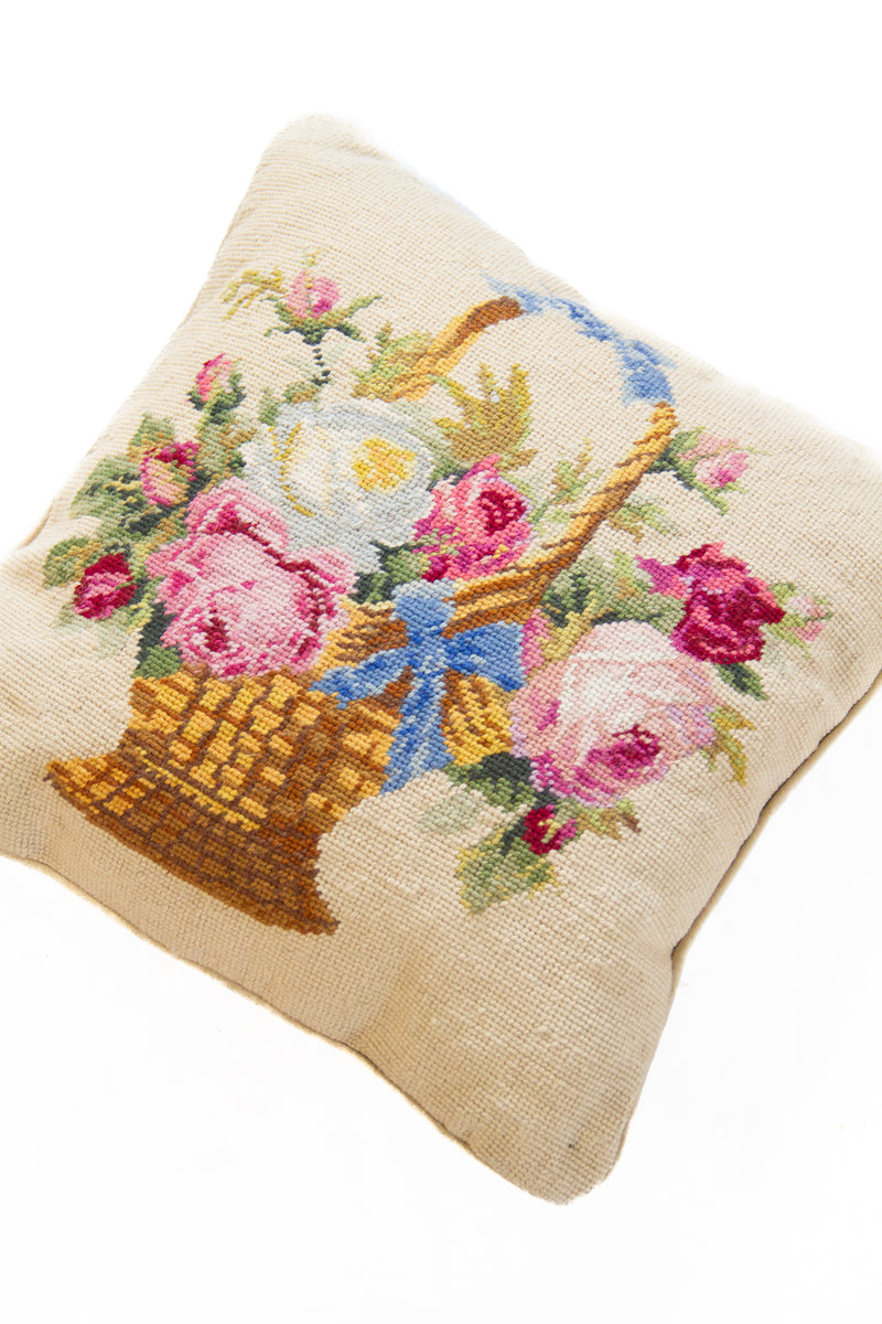 Detalle de textura de almohadón beige con flores, hojas y canasto en tonos rosas y azules