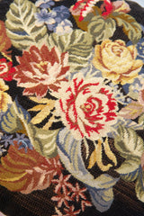 Detalle de textura de almohadón gobelino negro con flores en tonos rojo, amarillo y verde
