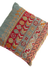 Detalle de textura de almohadón kilim con guardas geométricas, rombos y franjas en celeste y rojo