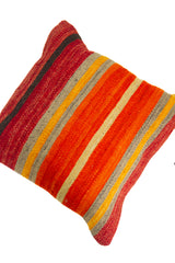 Detalle de textura de almohadón kilim con franjas horizontales en naranja, rojo, gris y beige