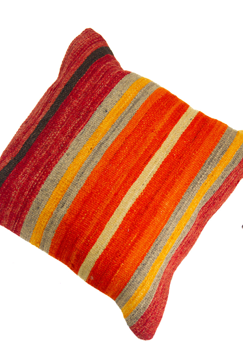 Detalle de textura de almohadón kilim con franjas horizontales en naranja, rojo, gris y beige