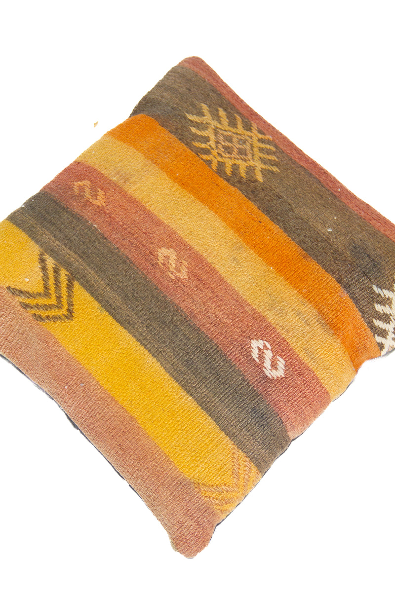 Detalle de textura de almohadón kilim con rayas verticales y motivos geométricos en tonos cálidos