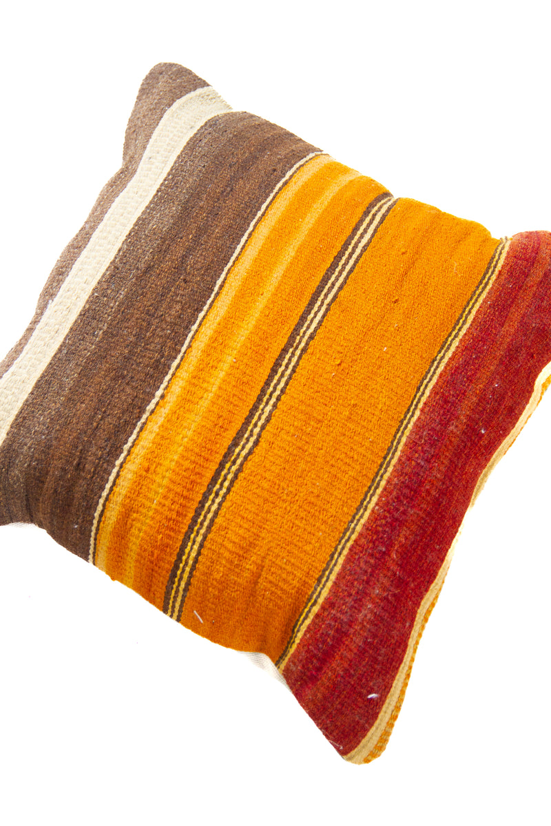 Detalle de textura de almohadón kilim con franjas horizontales en marrón, naranja y rojo