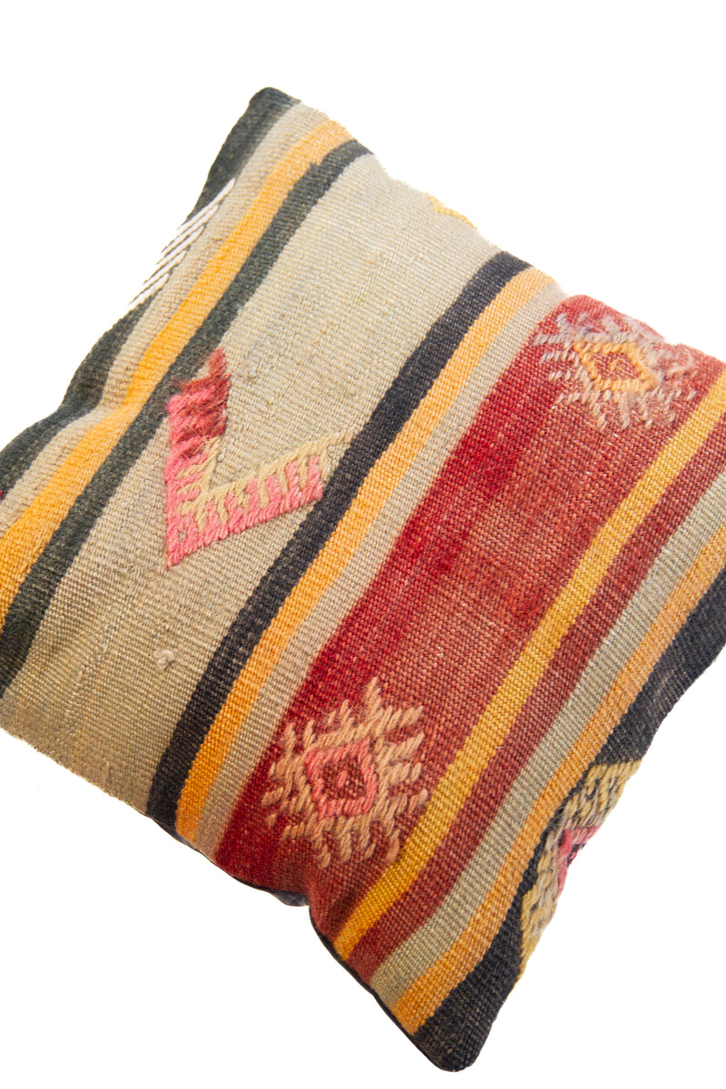Detalle de textura de almohadón kilim con rayas horizontales y motivos geométricos en tonos cálidos