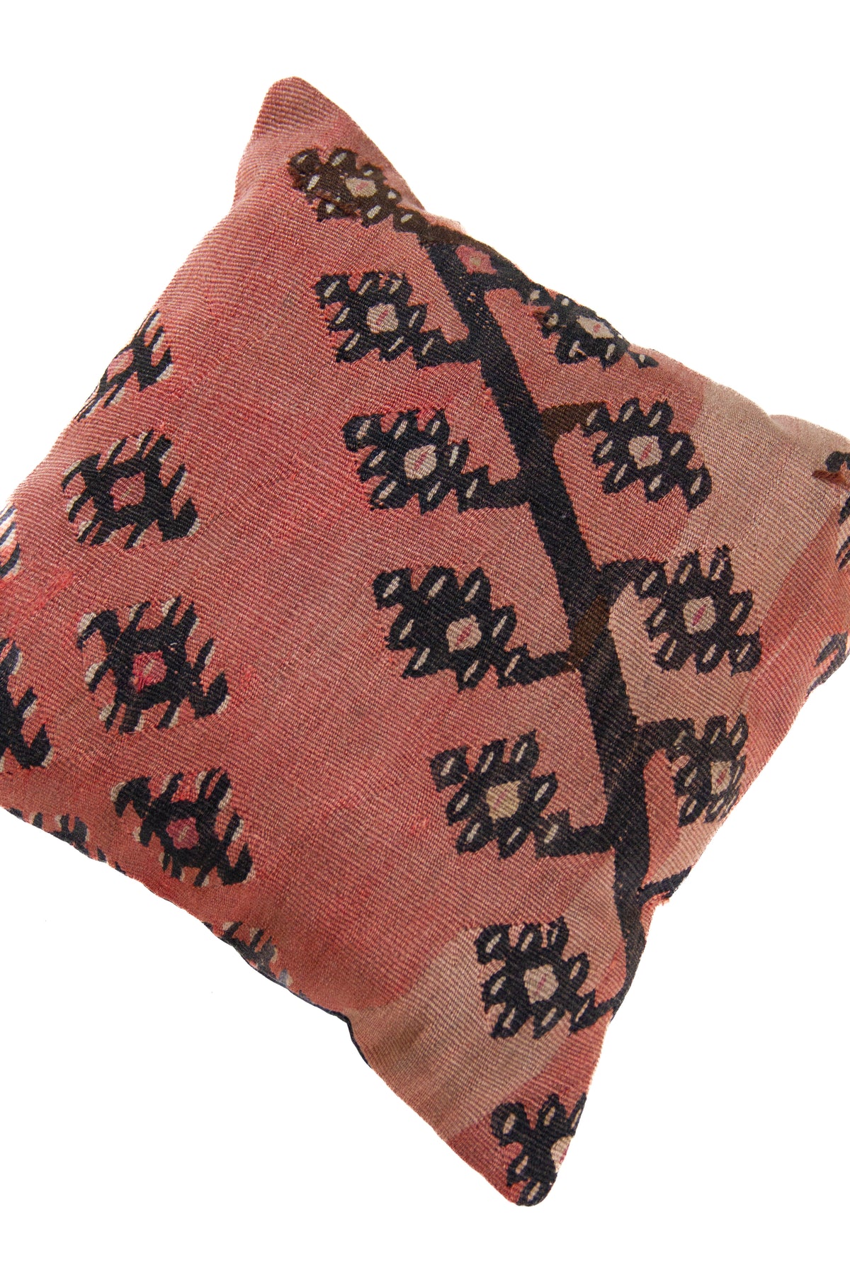 Detalle de textura del almohadón persa kilim rosado con motivos geométricos y florales en negro