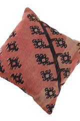 Detalle de textura del almohadón persa kilim rosado con motivos geométricos y florales en negro