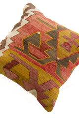 Detalle de textura de almohadón kilim con diseño geométrico y bordados en tonos cálidos