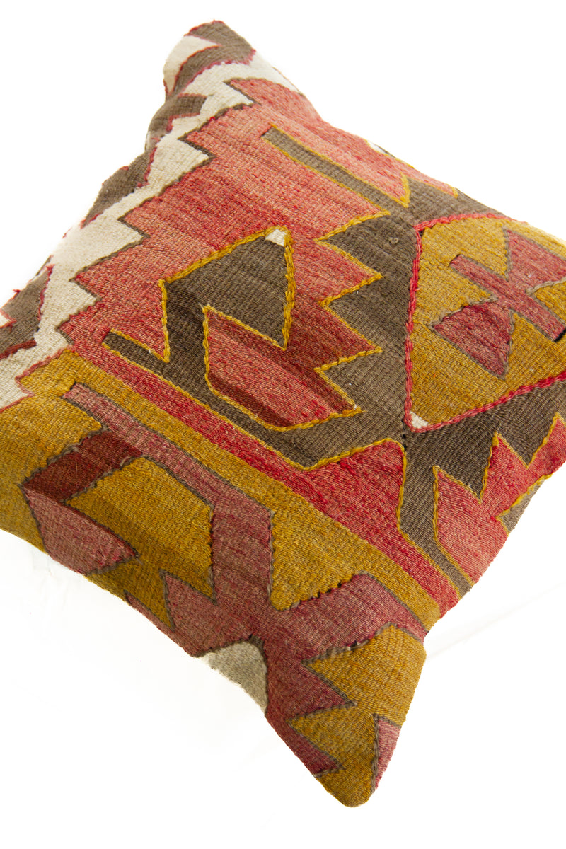 Detalle de textura de almohadón kilim con diseño geométrico y bordados en tonos cálidos