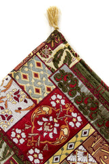 Almohadón decorativo rectangular con diseño geométrico en tonos rojos, verde y celeste.