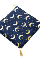 Detalle de textura de almohadón azul con patrón de lunas y estrellas doradas