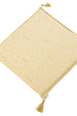 Detalle de textura de almohadón beige con patrón de lunas y estrellas en tono claro