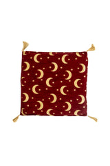 Almohadón cuadrado rojo con diseño de lunas doradas, estrellas y borlas en las esquinas