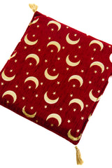 Detalle de textura de almohadón rojo con patrón de lunas y estrellas doradas
