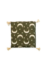 Almohadón cuadrado verde con diseño de lunas, estrellas y borlas en las esquinas.