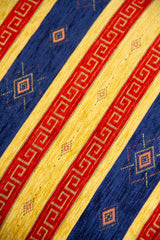 Detalle de textura de almohadón azul con guardas rojas, franjas beige y rombos decorativos