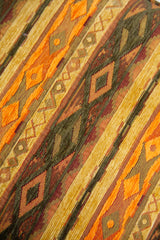 Detalle de textura de almohadón naranja con rombos, guardas y franjas decorativas