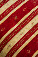 Detalle de textura de almohadón rojo con rayas beige, grecas y rombos decorativos
