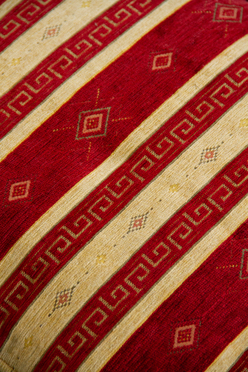Detalle de textura de almohadón rojo con rayas beige, grecas y rombos decorativos