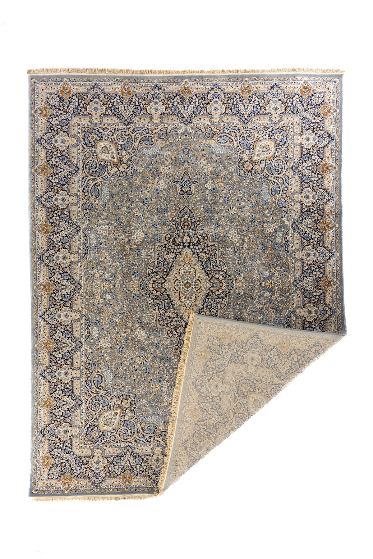Alfombra gris y azul con una esquina doblada mostrando el reverso y los flecos en detalle.