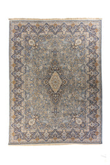 Vista cenital completa de la alfombra con diseño simétrico floral en tonos suaves de gris, azul y dorado.