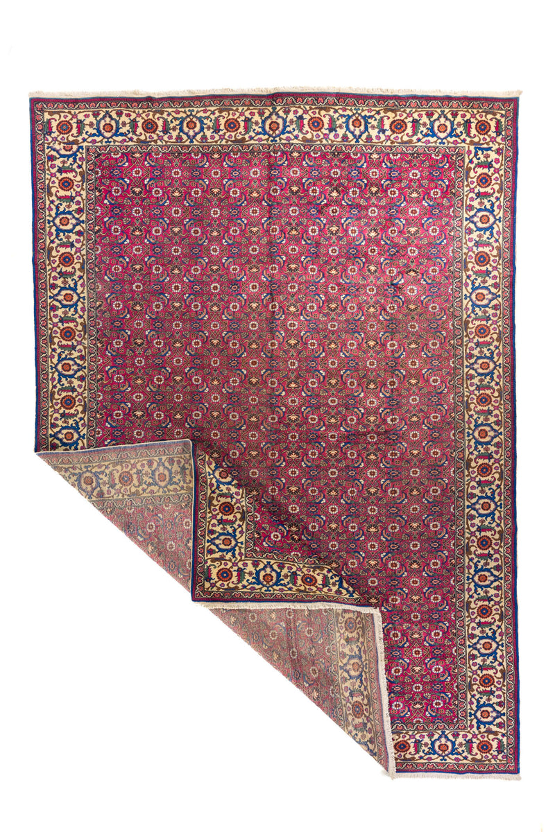 Alfombra oriental roja con esquina doblada que muestra el reverso y la flexibilidad del tejido