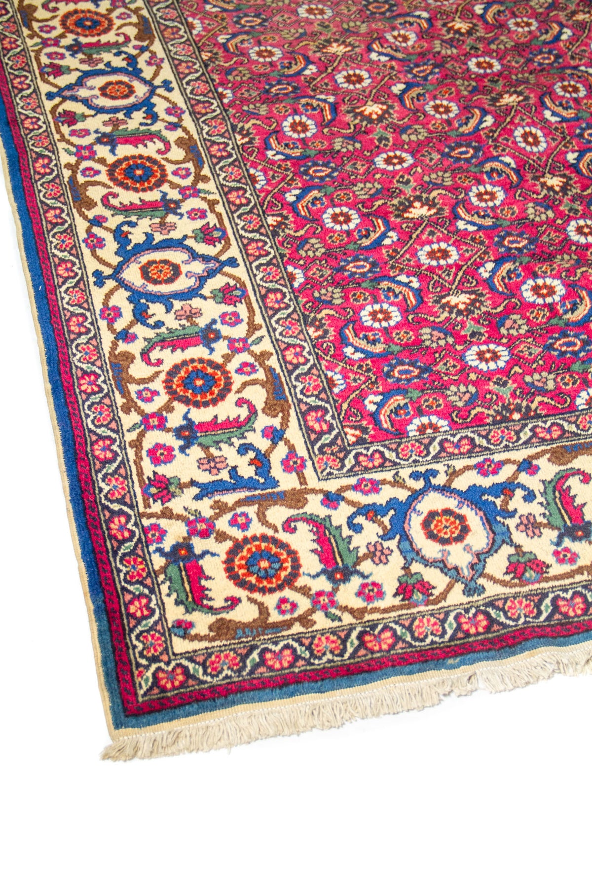 Detalle lateral de alfombra clásica roja con cenefa beige y motivos florales tradicionales