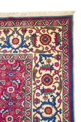 Primer plano de borde de alfombra oriental roja con guarda beige, flores estilizadas y acabado artesanal