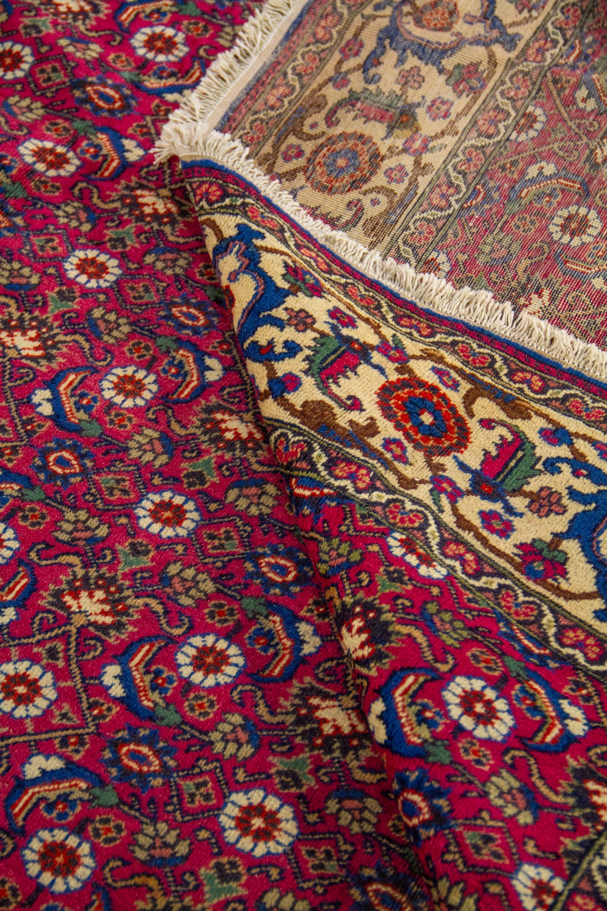 Alfombra roja doblada en detalle con patrón floral repetitivo y guarda beige decorativa