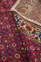 Alfombra roja doblada en detalle con patrón floral repetitivo y guarda beige decorativa