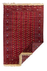 Alfombra roja estilo Bokhara con detalle del reverso y flecos artesanales visibles.