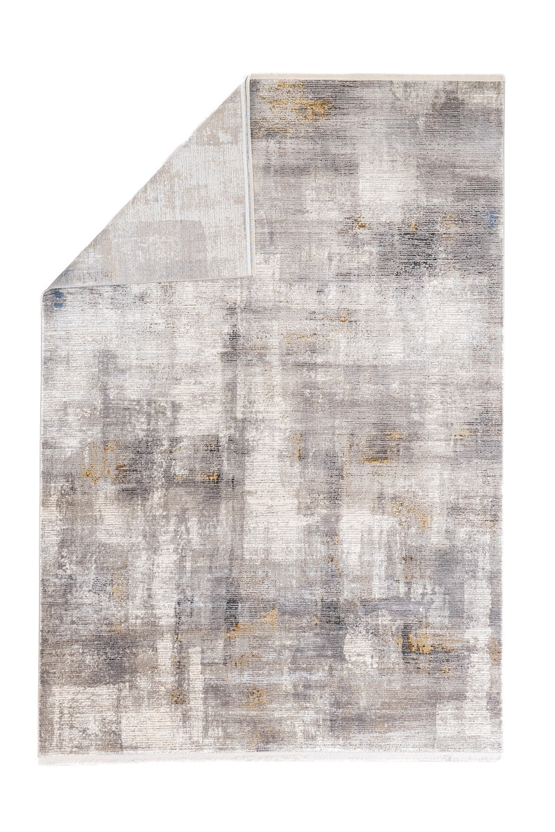 Alfombra moderna con esquina doblada, mostrando su reverso y diseño abstracto en tonos neutros.