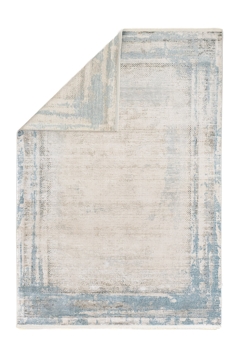 Alfombra contemporánea mostrada con una esquina doblada, revelando la parte posterior del tejido en tonos claros.