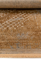 Primer plano del borde de la alfombra, con detalles ornamentales en dorado y gris sobre textura envejecida.