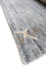 Detalle cercano de la orilla de la alfombra con diseño floral en beige y marrón sobre fondo azul claro