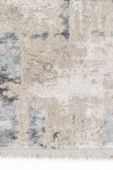 Primer plano del borde de la alfombra con textura en relieve en tonos grises y beige.