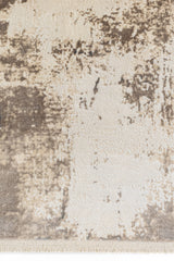 Detalle del borde inferior de la alfombra con textura densa y combinación de tonos claros y marrones.