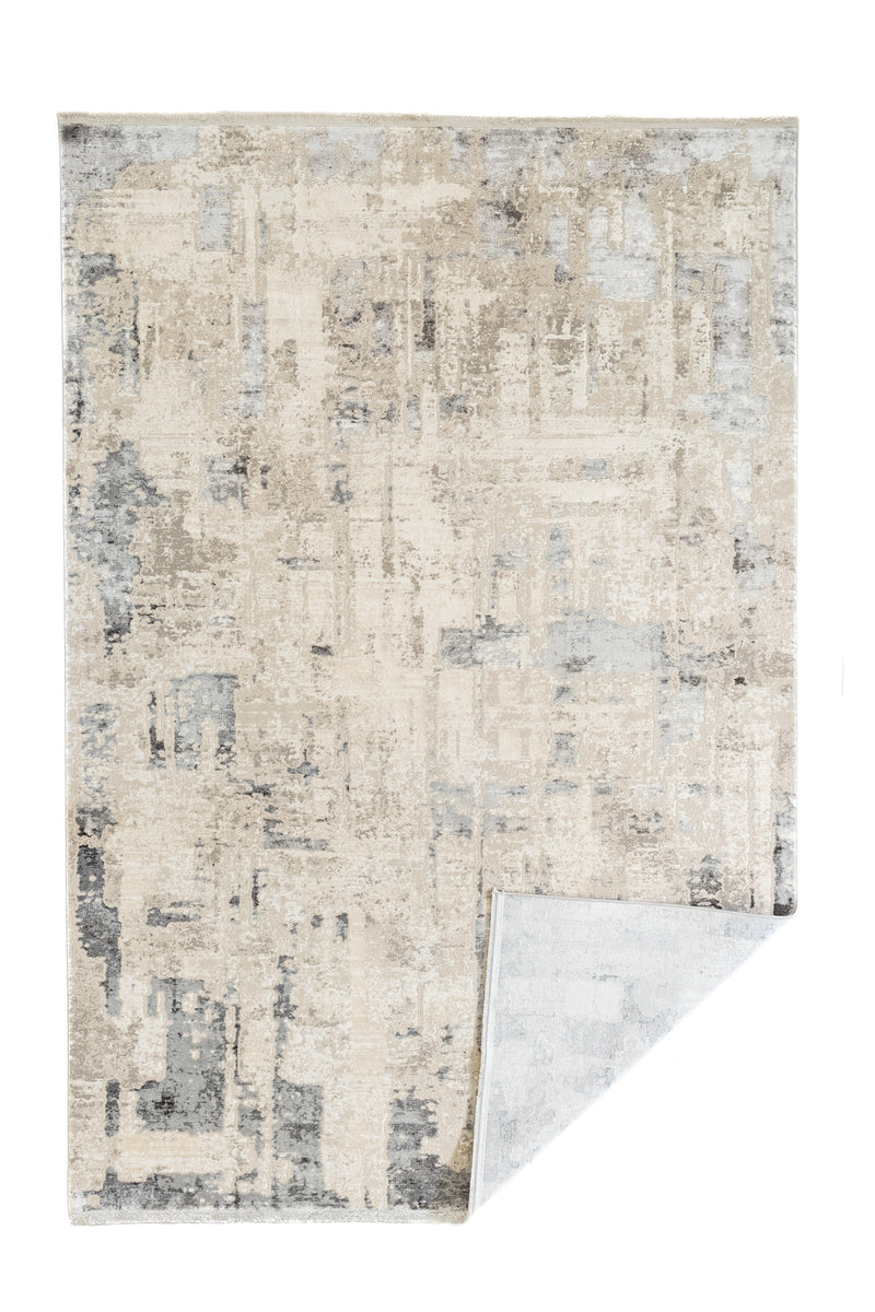 Alfombra con esquina doblada mostrando el reverso, destacando su diseño moderno en tonos fríos.