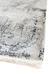 Primer plano del borde inferior de la alfombra con textura densa y mezcla de colores oscuros y claros.