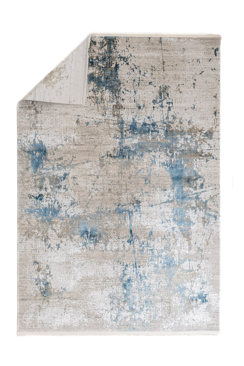 Alfombra contemporánea con la esquina doblada, mostrando diseño abstracto en tonos fríos y cálidos.